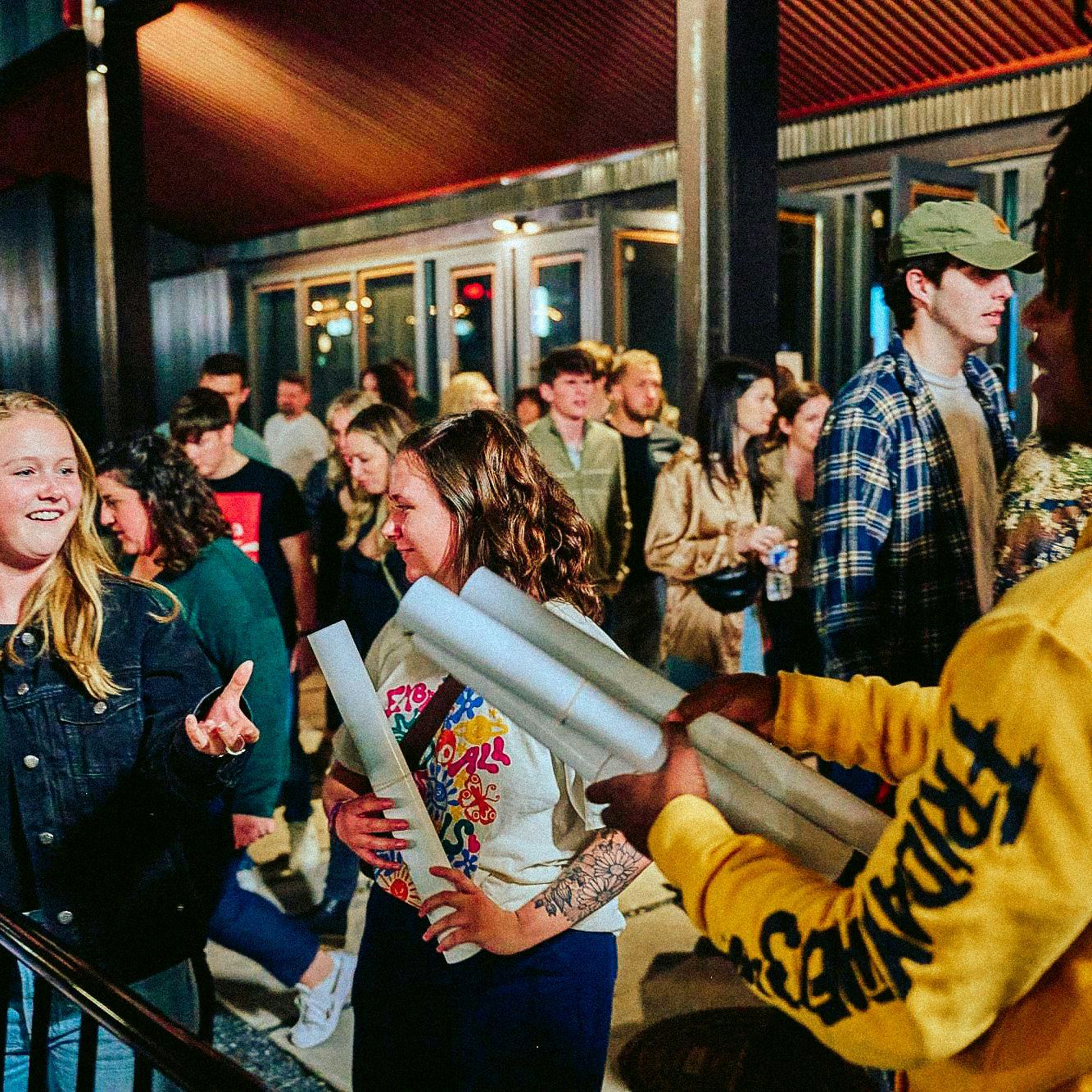 man passing out posters to fans after the concert